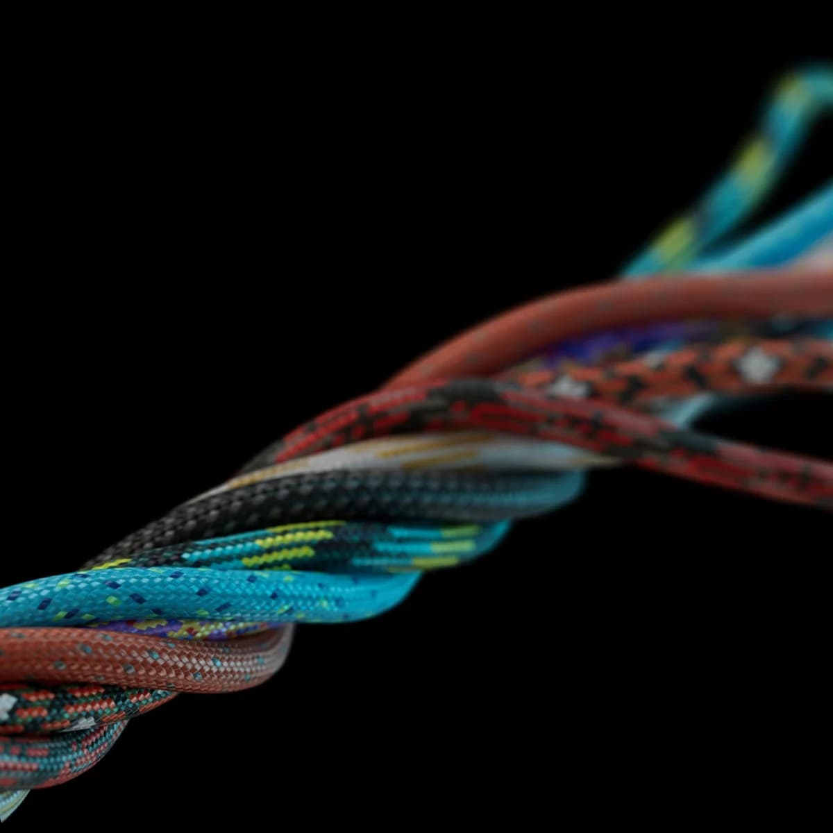 Close-up of coloured climbing ropes twisted into a single braid against a black background, the near strands sharp and the far ones falling out of focus