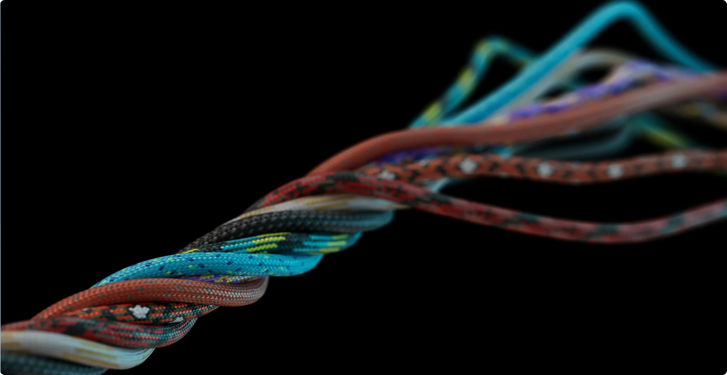 Close-up of coloured climbing ropes twisted into a single braid against a black background, the near strands sharp and the far ones falling out of focus